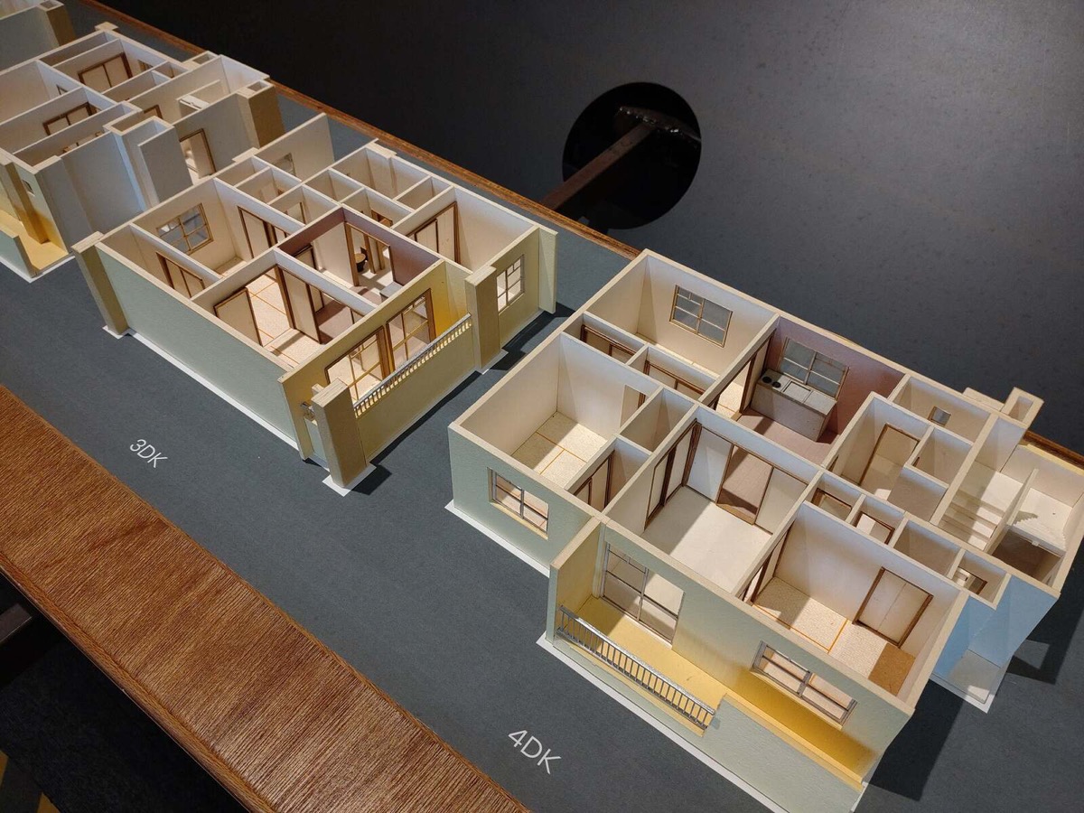 団地の間取りの模型。3DKと4DKの部屋が、壁と窓、ベランダまで作り込まれ、上から見下ろす形で並んでいる